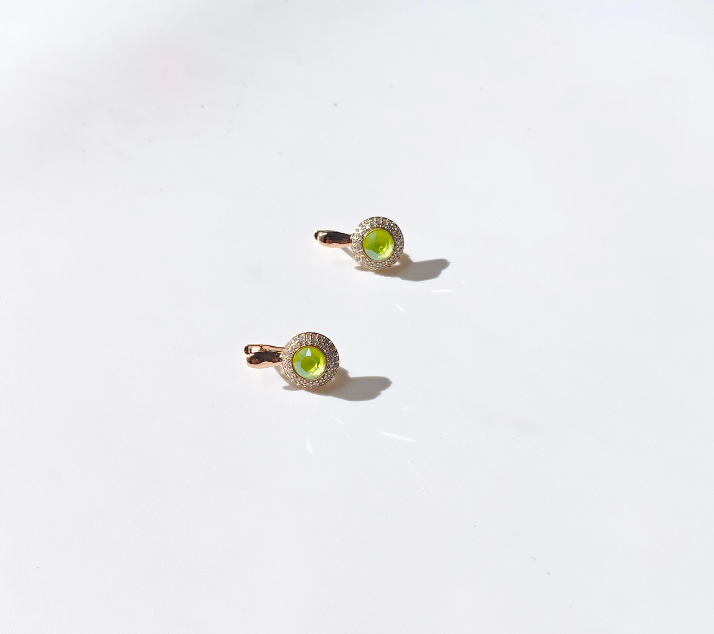 Two gold rings with green gemstones on a white background