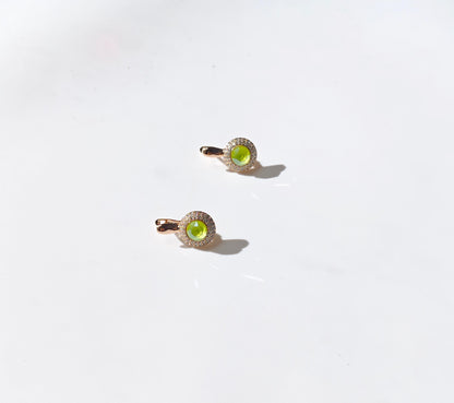 Two gold rings with green gemstones on a white background