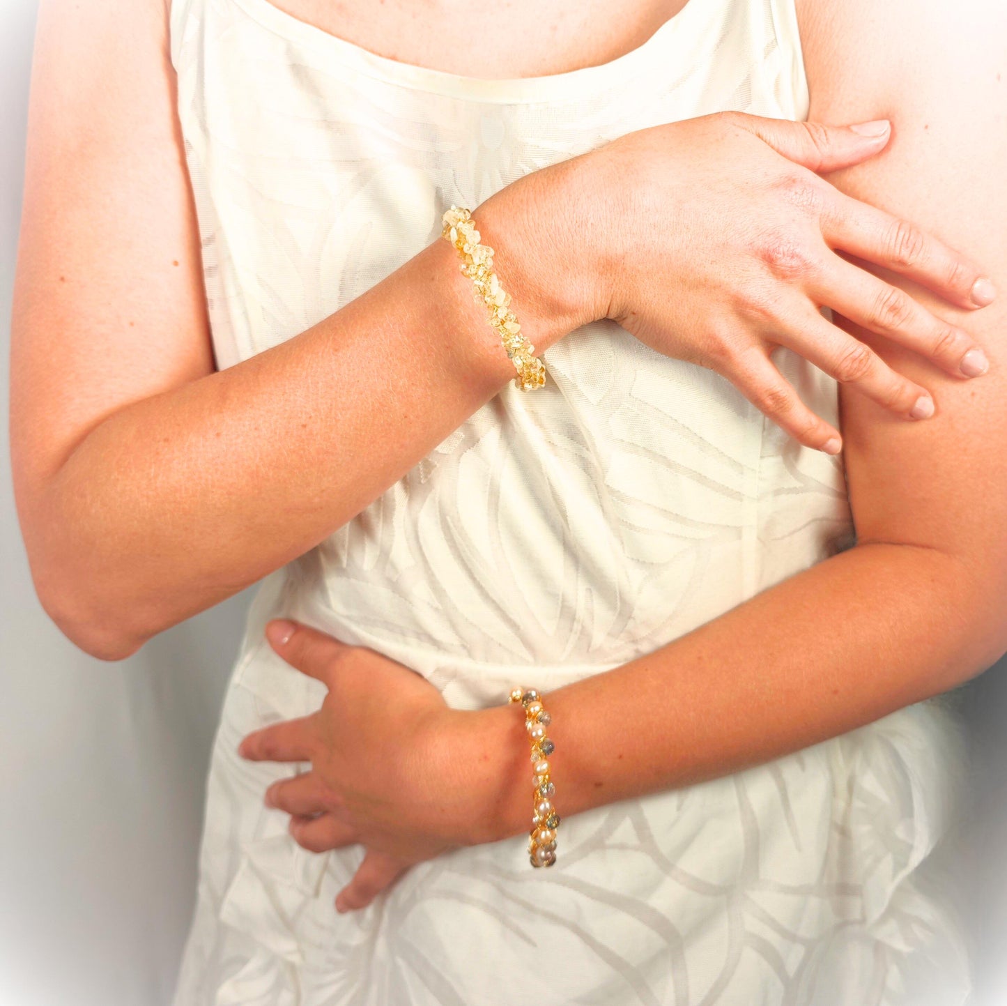 Person wearing a gold bracelet on a plain background