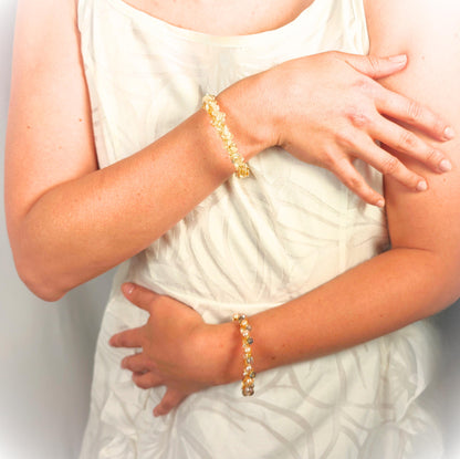 Person wearing a gold bracelet on a plain background