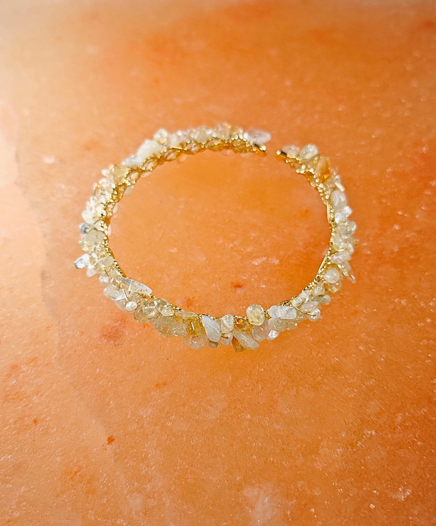 Gold bracelet with embedded stones on a peach-colored surface