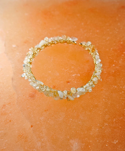 Gold bracelet with embedded stones on a peach-colored surface