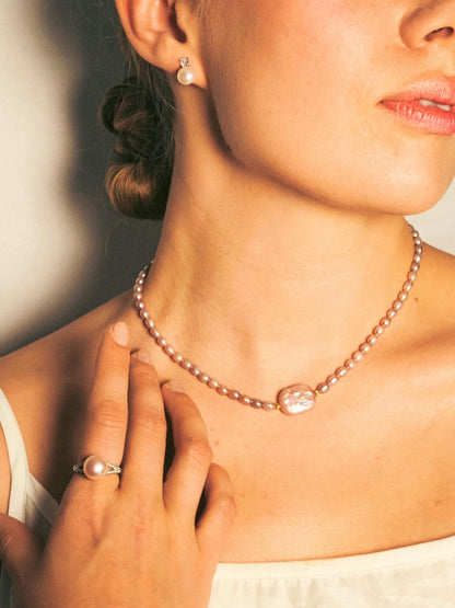 Woman wearing a pearl necklace and earrings with a soft background