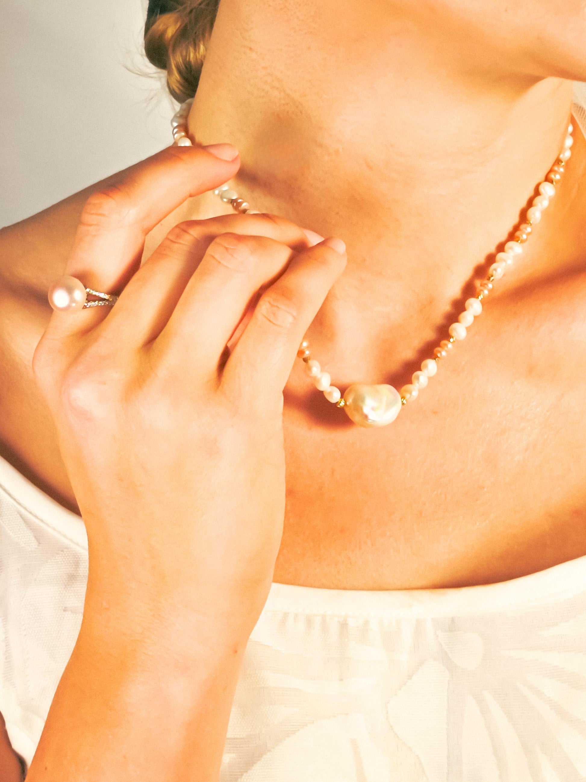 Close-up of a person wearing a pearl necklace with a blurred background