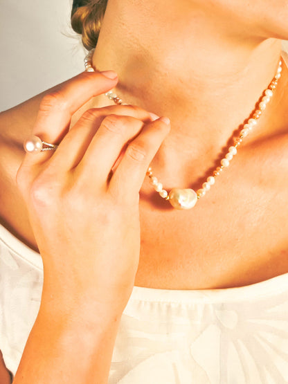 Close-up of a person wearing a pearl necklace with a blurred background