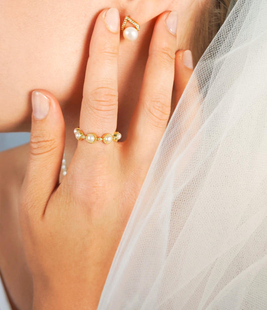 Close-up of a hand wearing pearl rings with a soft background