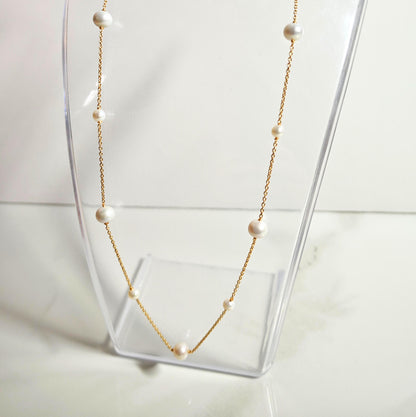Pearl necklace on a clear stand with a white background