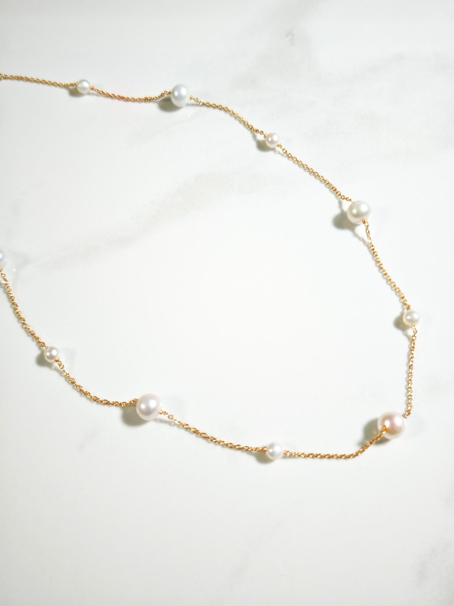 Pearl necklace with gold chain on a white background