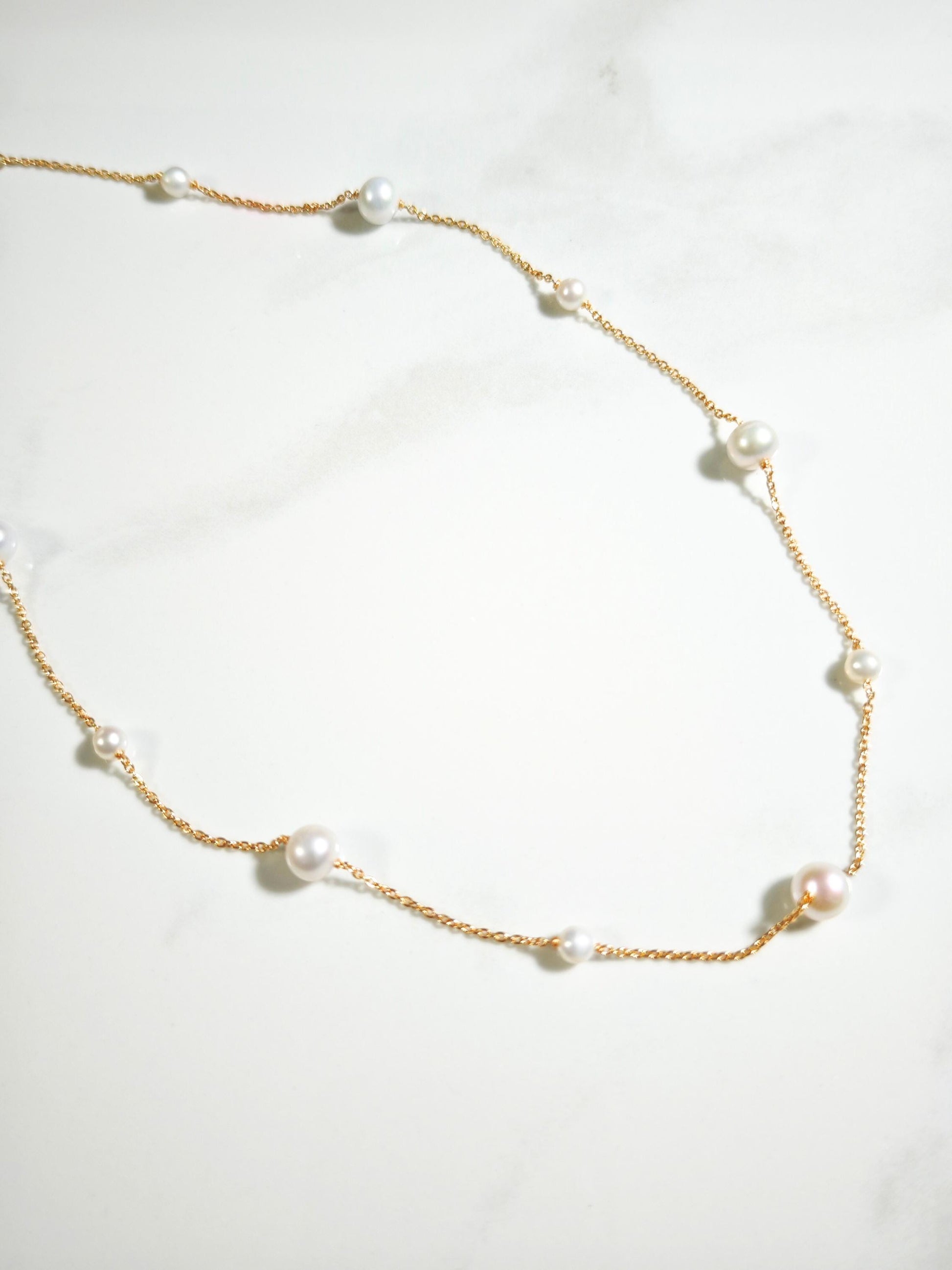 Pearl necklace with gold chain on a white background