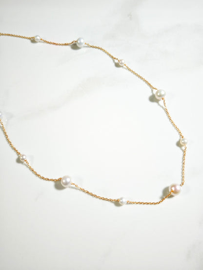 Pearl necklace with gold chain on a white background