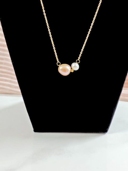 Gold necklace with three pearls on a black stand