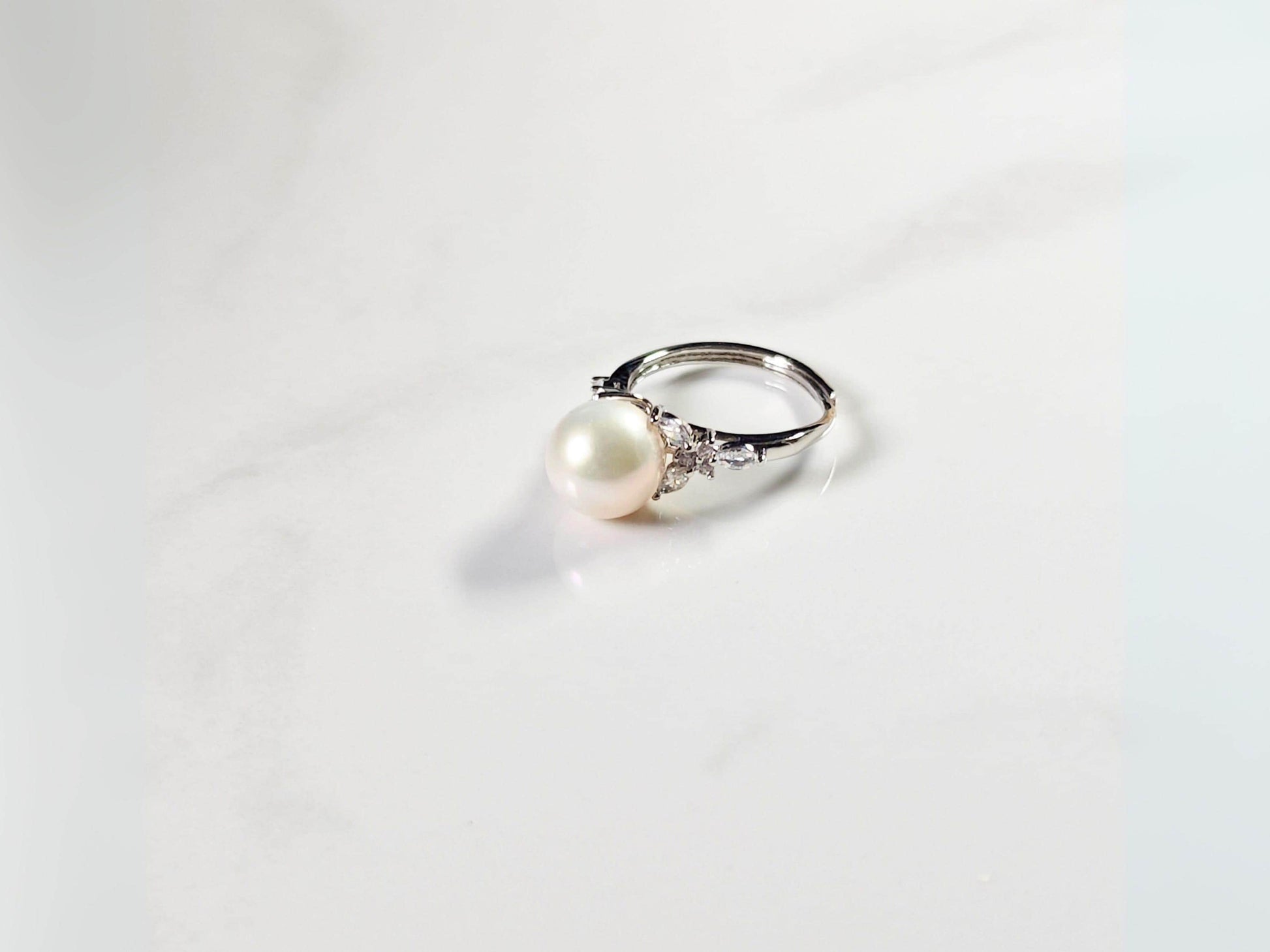 Pearl ring with silver band on a white background