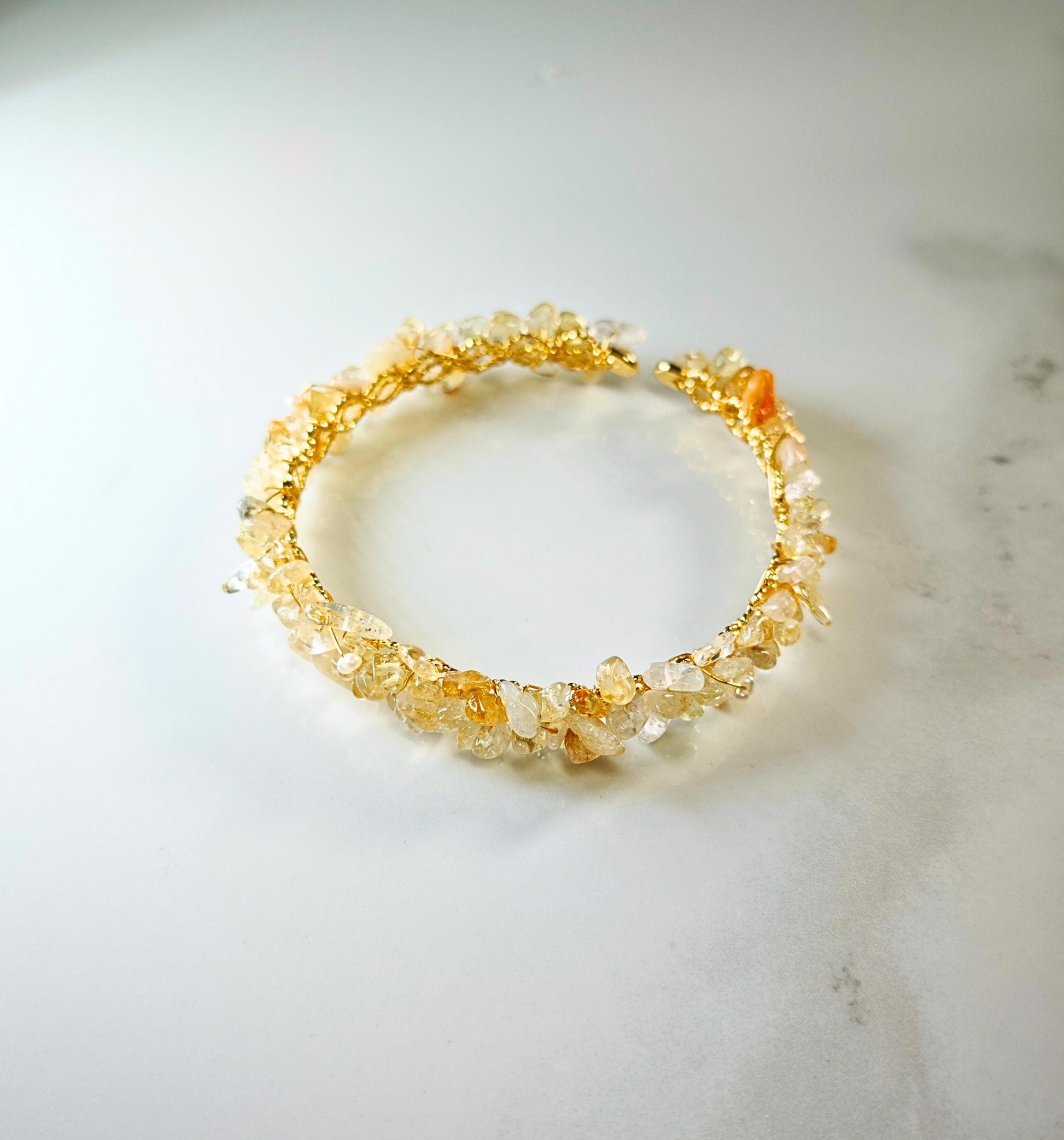 Gold bracelet with embedded stones on a light marble surface