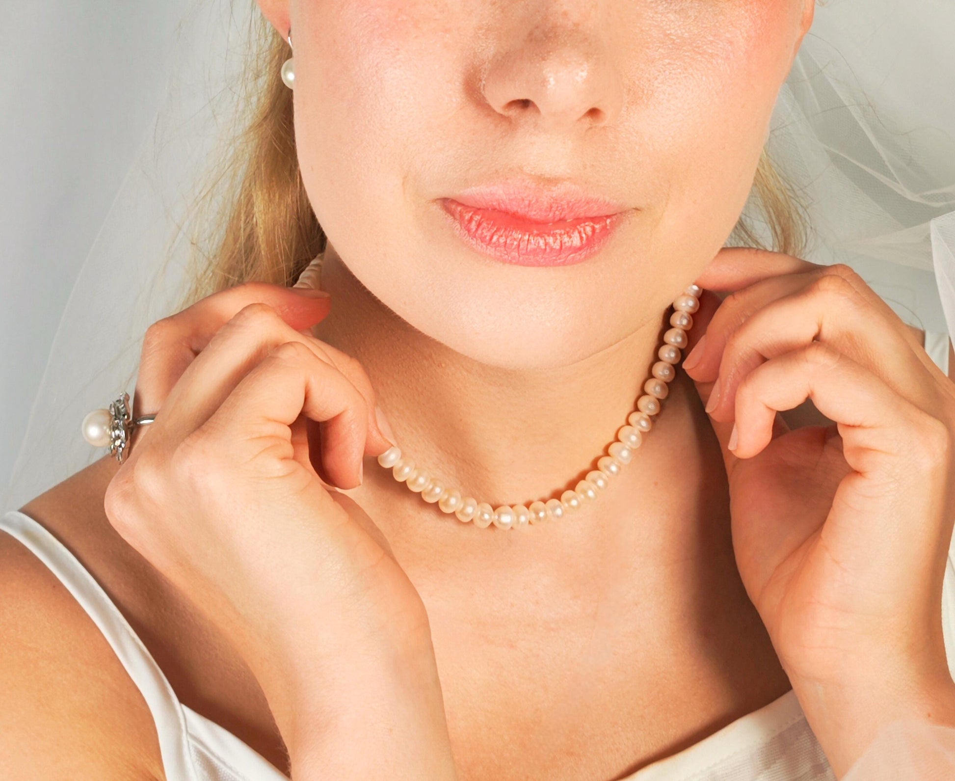 Close-up of a woman wearing a pearl necklace with a plain background