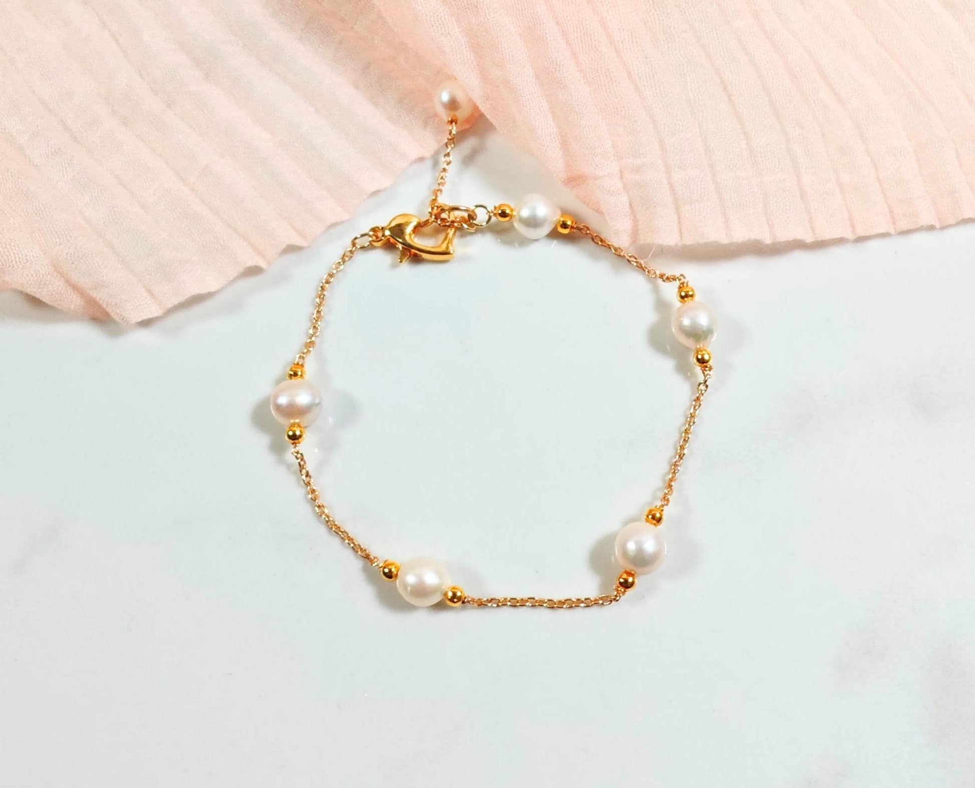 Pearl bracelet with gold chain on a light background