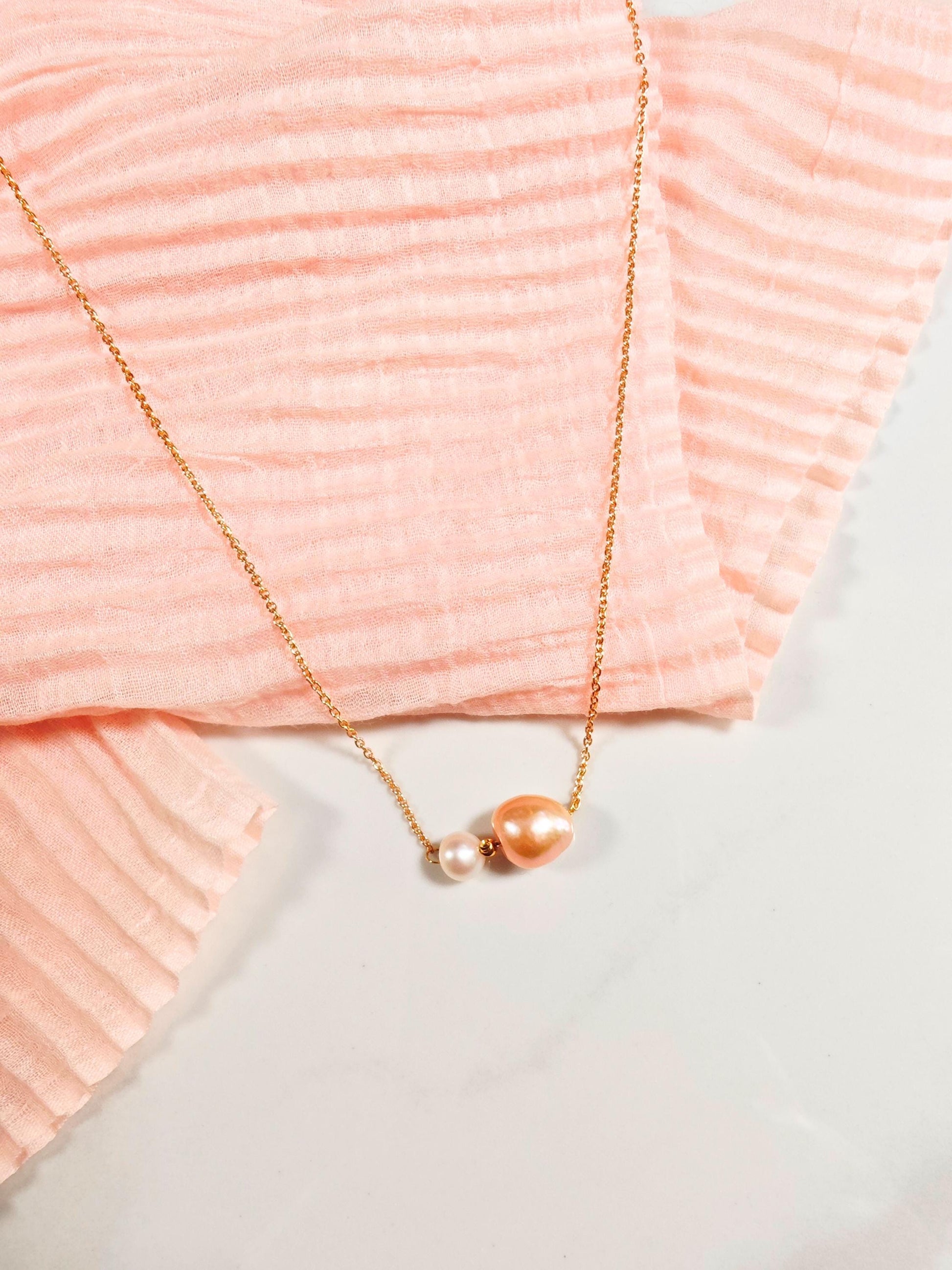 Gold necklace with a pendant on a pink textured fabric background