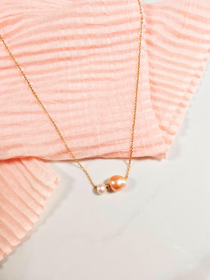 Gold necklace with a pendant on a pink textured fabric background