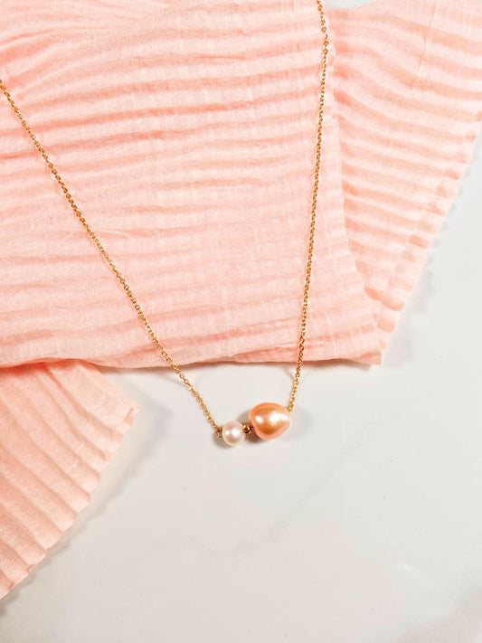 Gold necklace with a pendant on a pink textured fabric background