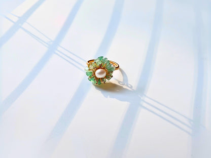 Gold ring with green gemstones on a light blue background