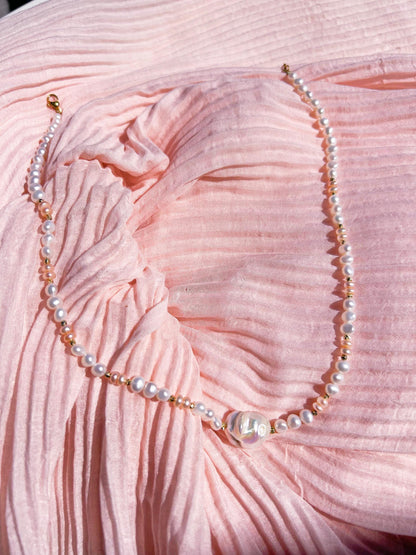 Pearl necklace on a pink textured fabric background