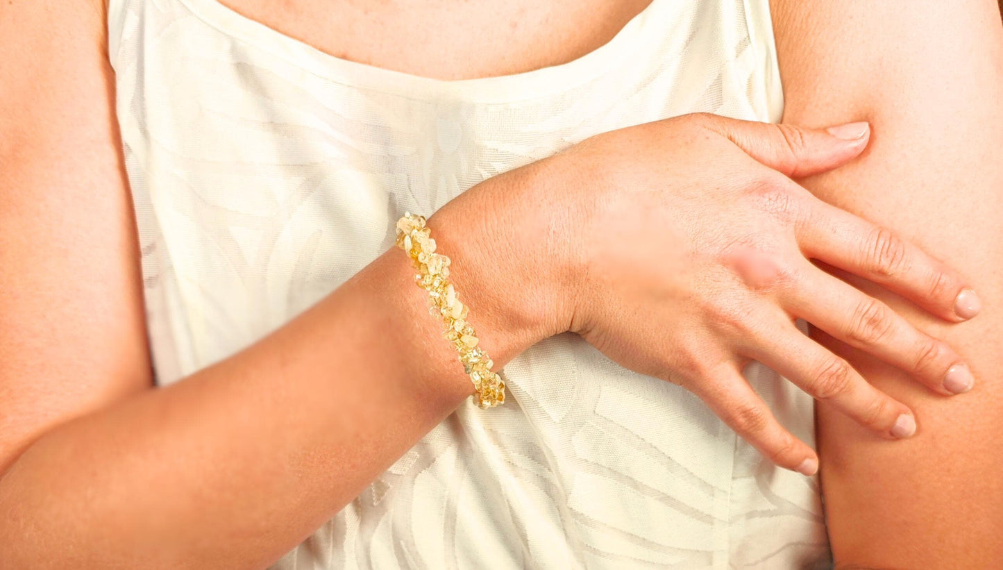 Close-up of a person wearing a gold bracelet on a light background
