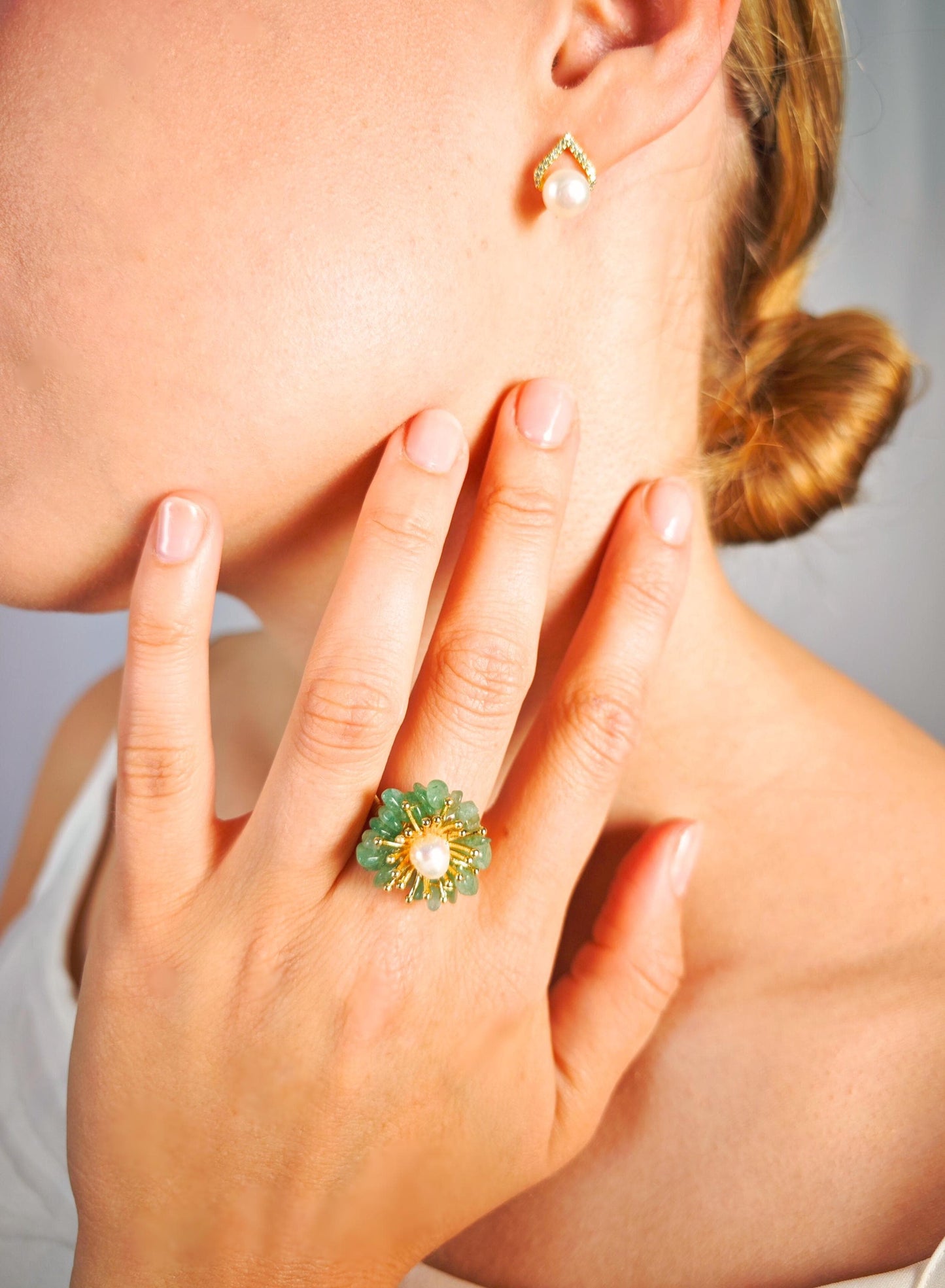 Close-up of a hand wearing a green ring with a blurred background