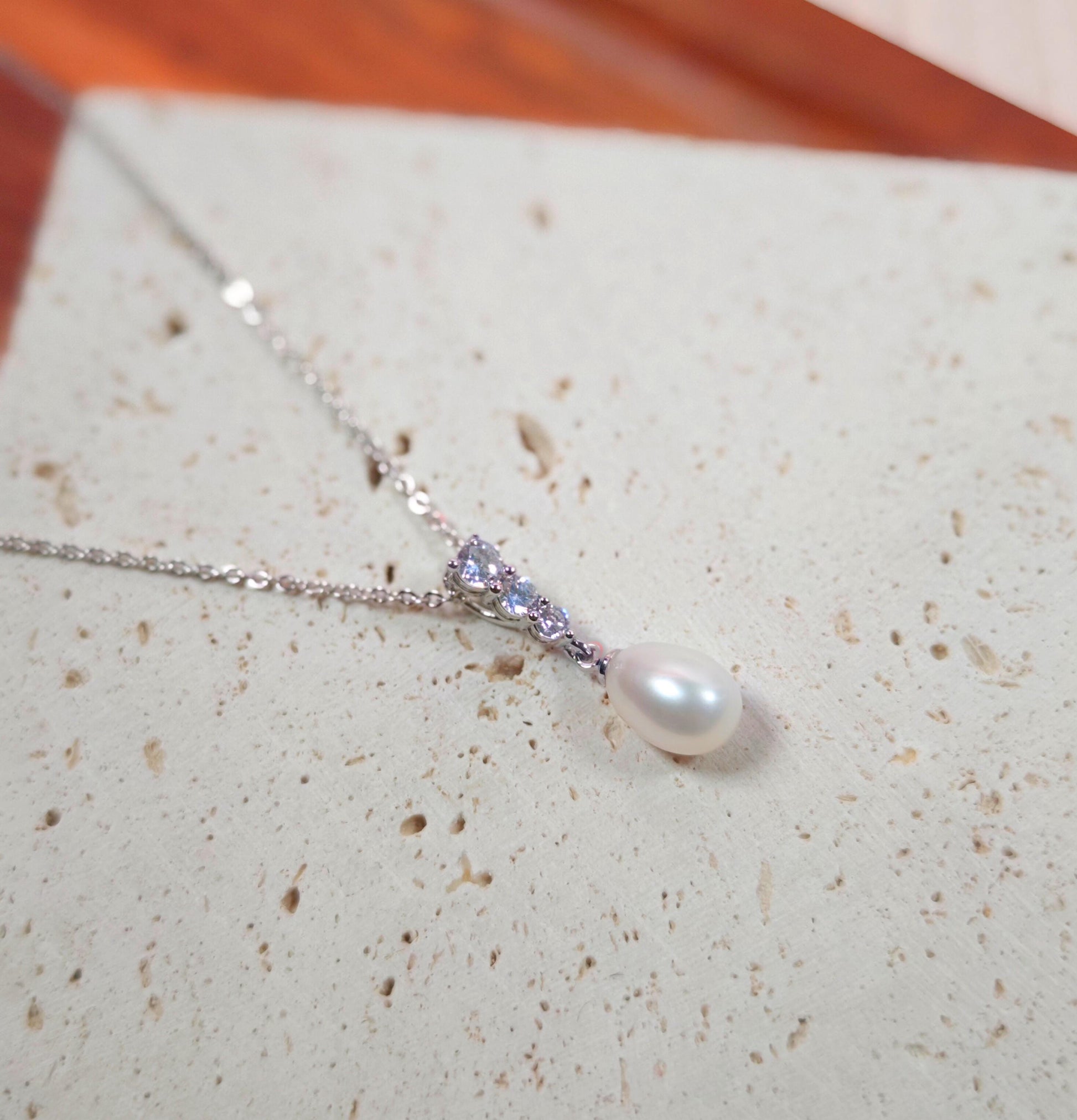 Pearl necklace with a silver chain on a textured surface