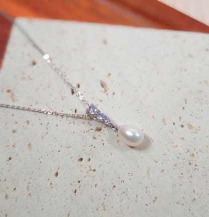 Pearl necklace with a silver chain on a textured surface