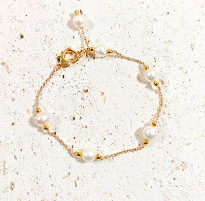 Pearl bracelet with gold accents on a textured beige surface