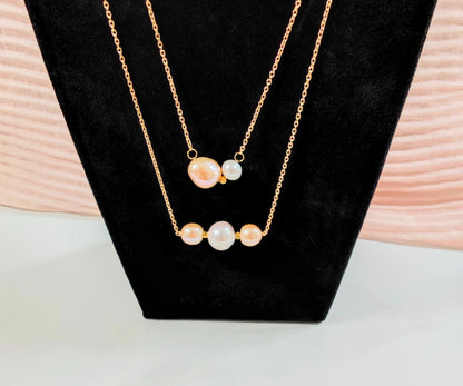 Gold necklace with pearl-like beads on a black stand with a light wooden background