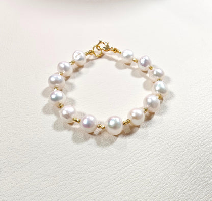 Pearl bracelet with gold accents on a light gray background