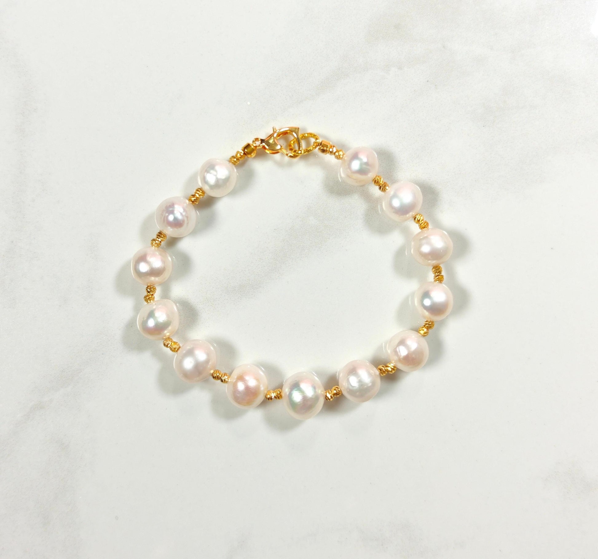 Pearl bracelet with gold clasp on a white background