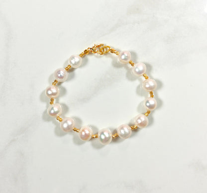 Pearl bracelet with gold clasp on a white background