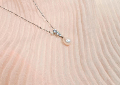 Pearl necklace with small crystals on a soft pink fabric background