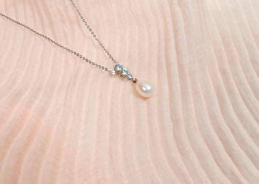 Pearl necklace with small crystals on a soft pink fabric background