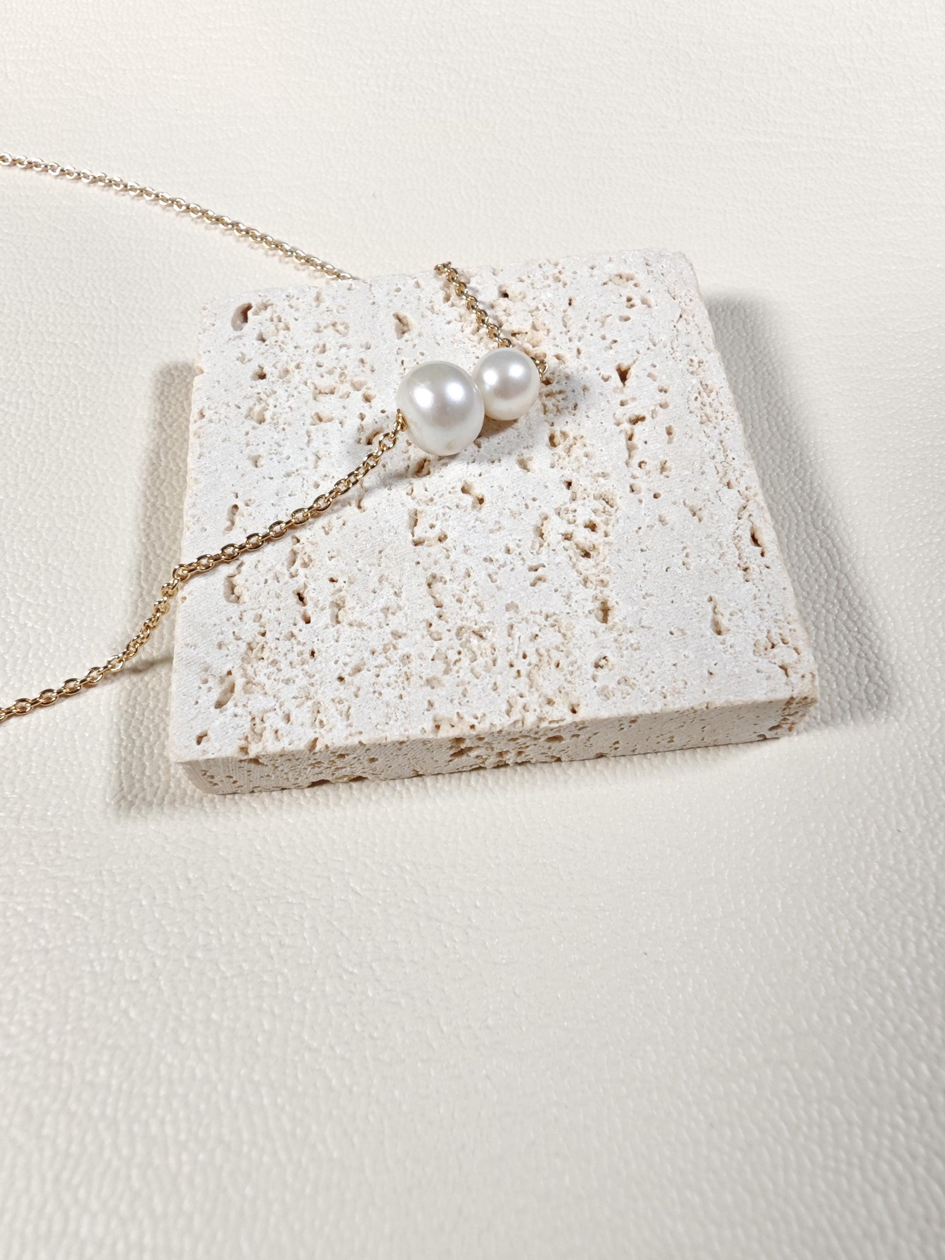 Pearl necklace on a textured stone surface with a light background