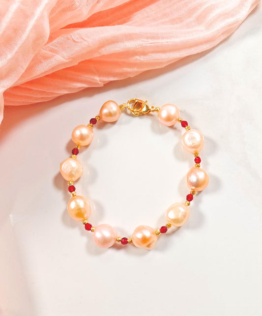 Pearl bracelet with red beads on a white surface with pink fabric
