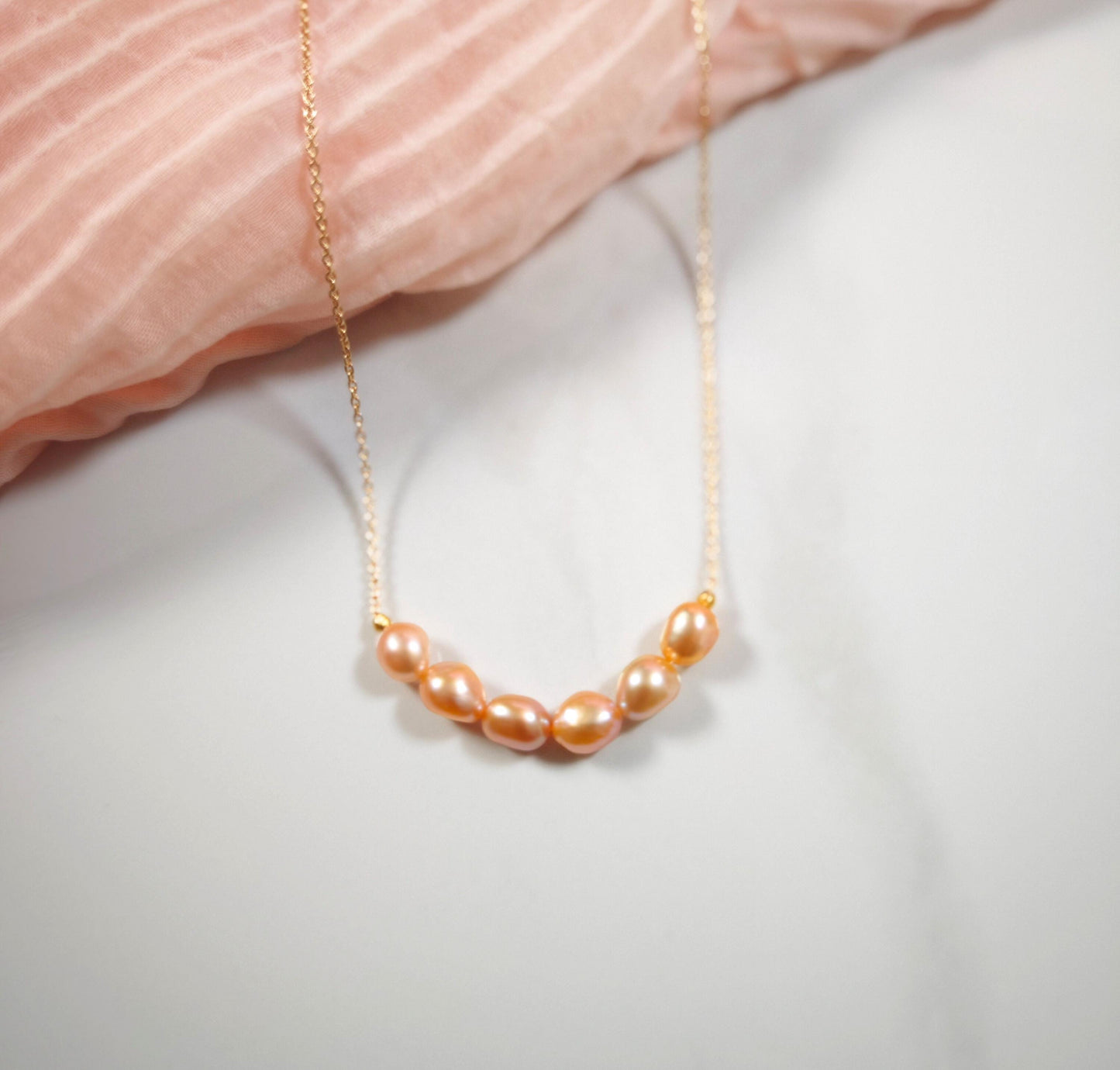 Pearl necklace on a soft pink fabric background