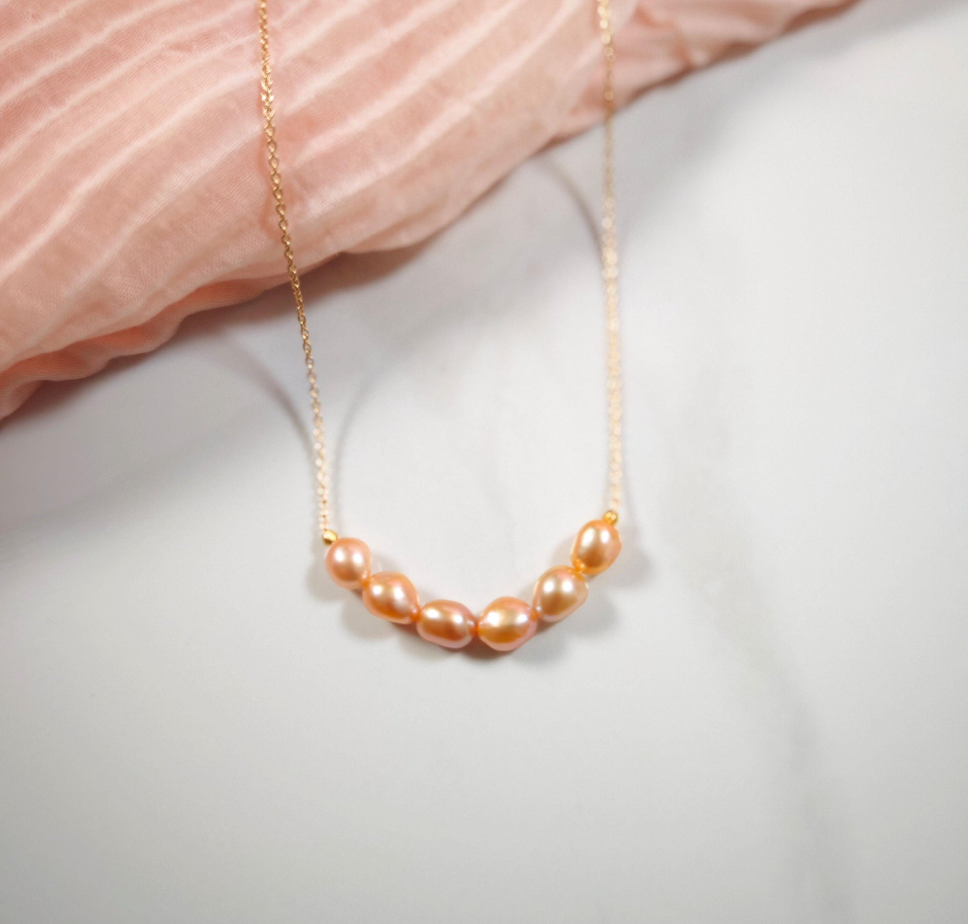 Pearl necklace on a soft pink fabric background