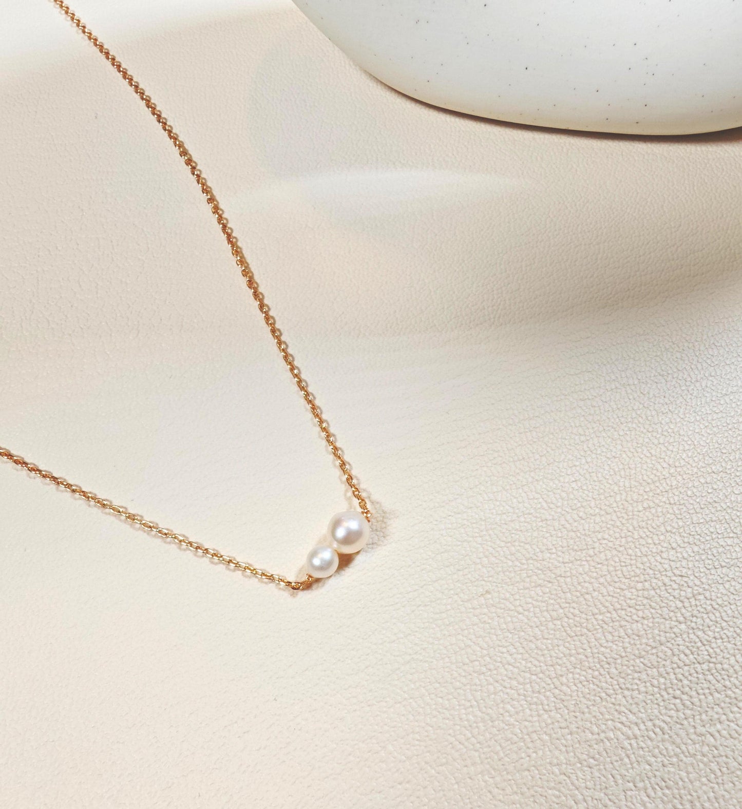 Delicate pearl necklace on a light beige surface