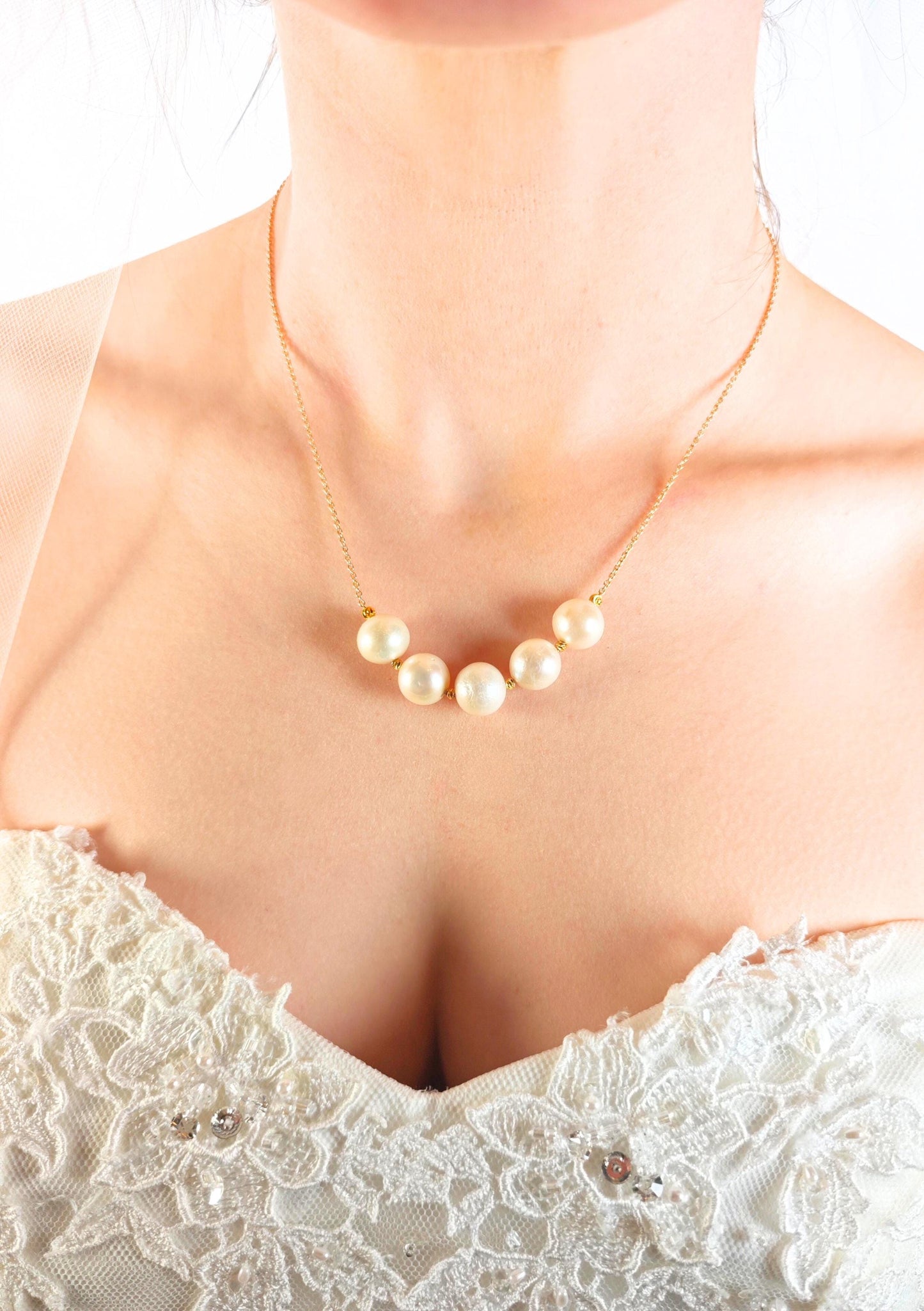 Pearl necklace worn by a person in a white lace garment