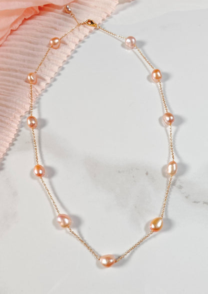 Pearl necklace with gold chain on a light background