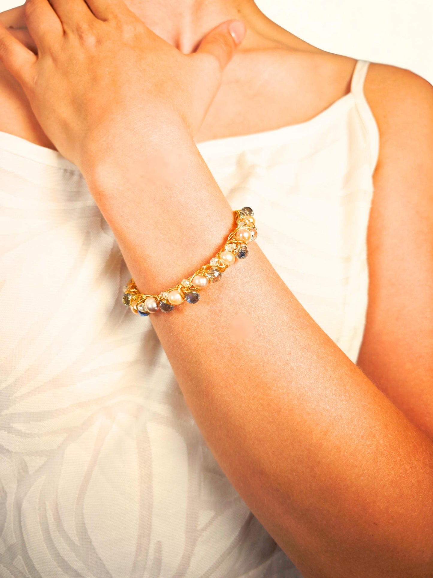 Close-up of a wrist wearing a beaded bracelet with a neutral background