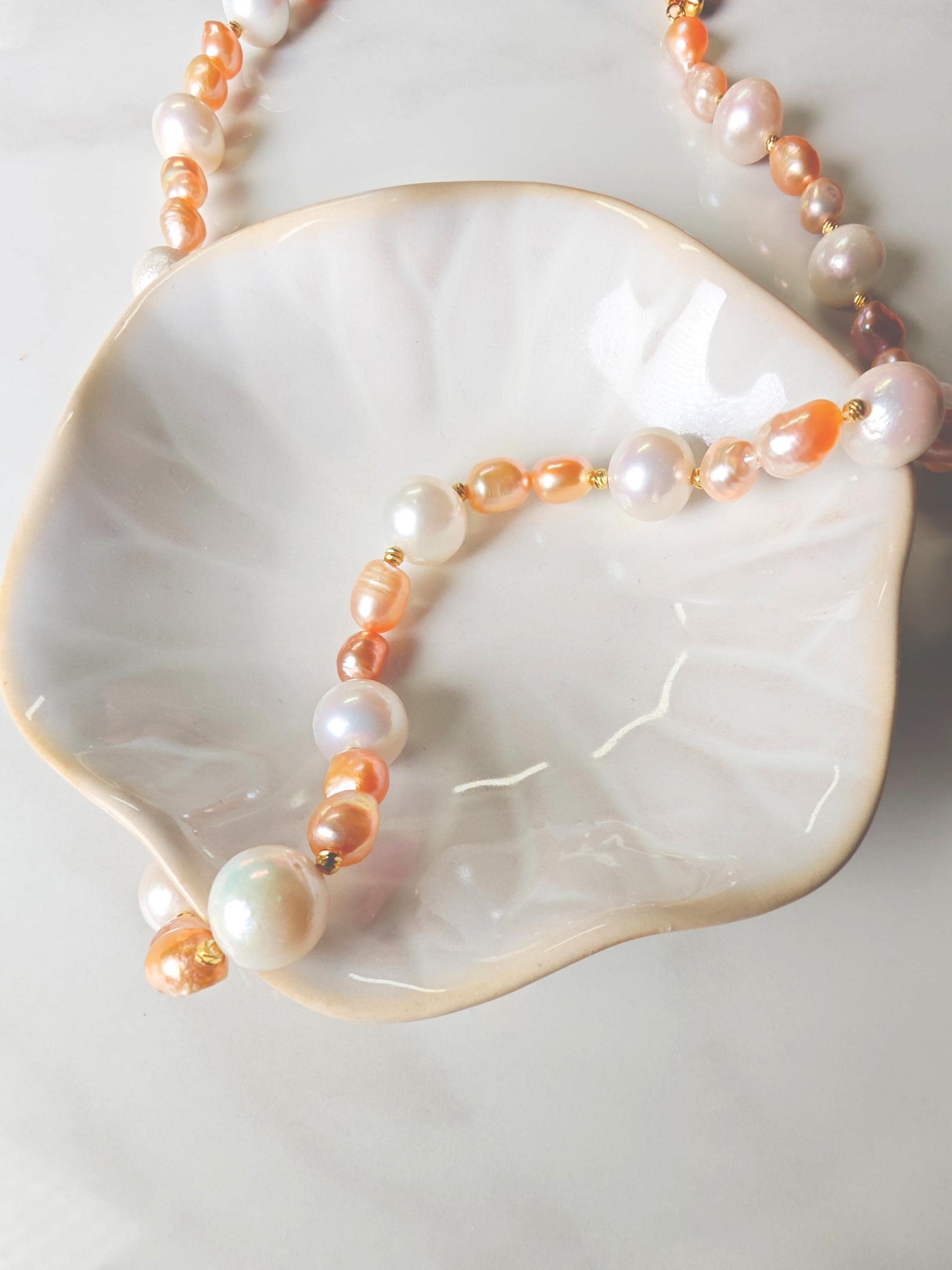 Pearl and peach bead necklace on a white shell