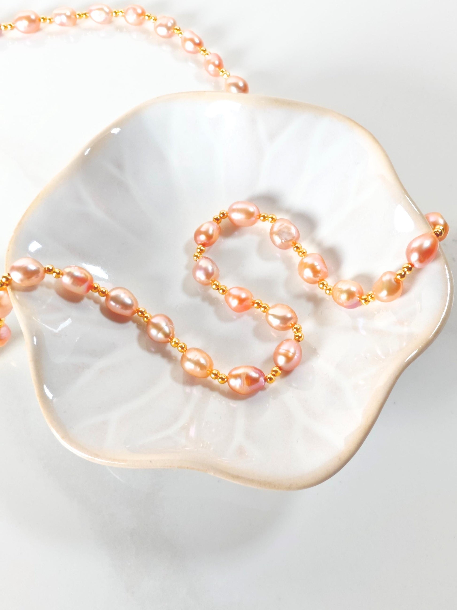 Pearl necklace on a white dish with a gold chain