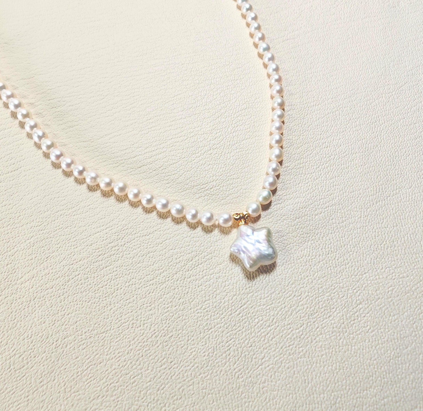 Pearl necklace with a star-shaped pendant on a light beige background