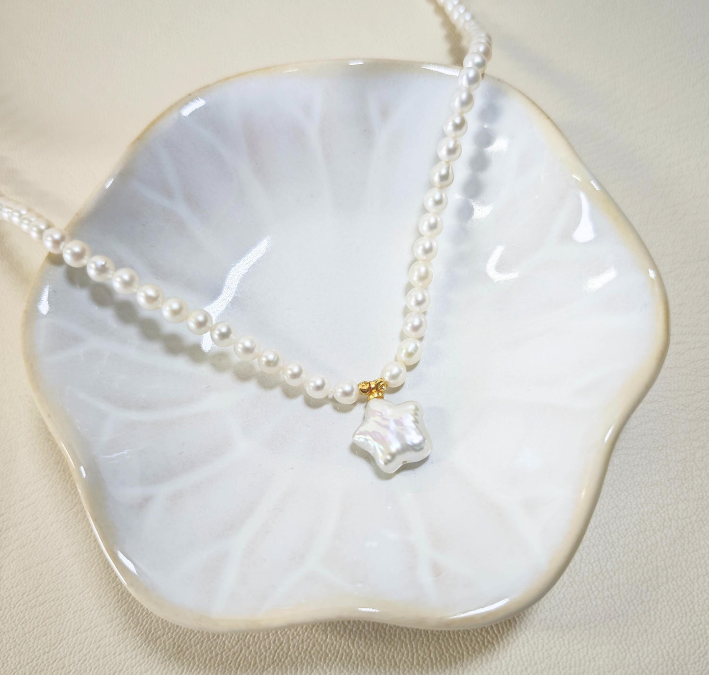 Pearl necklace with a unique pendant on a white dish