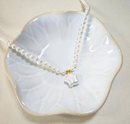 Pearl necklace with a unique pendant on a white dish