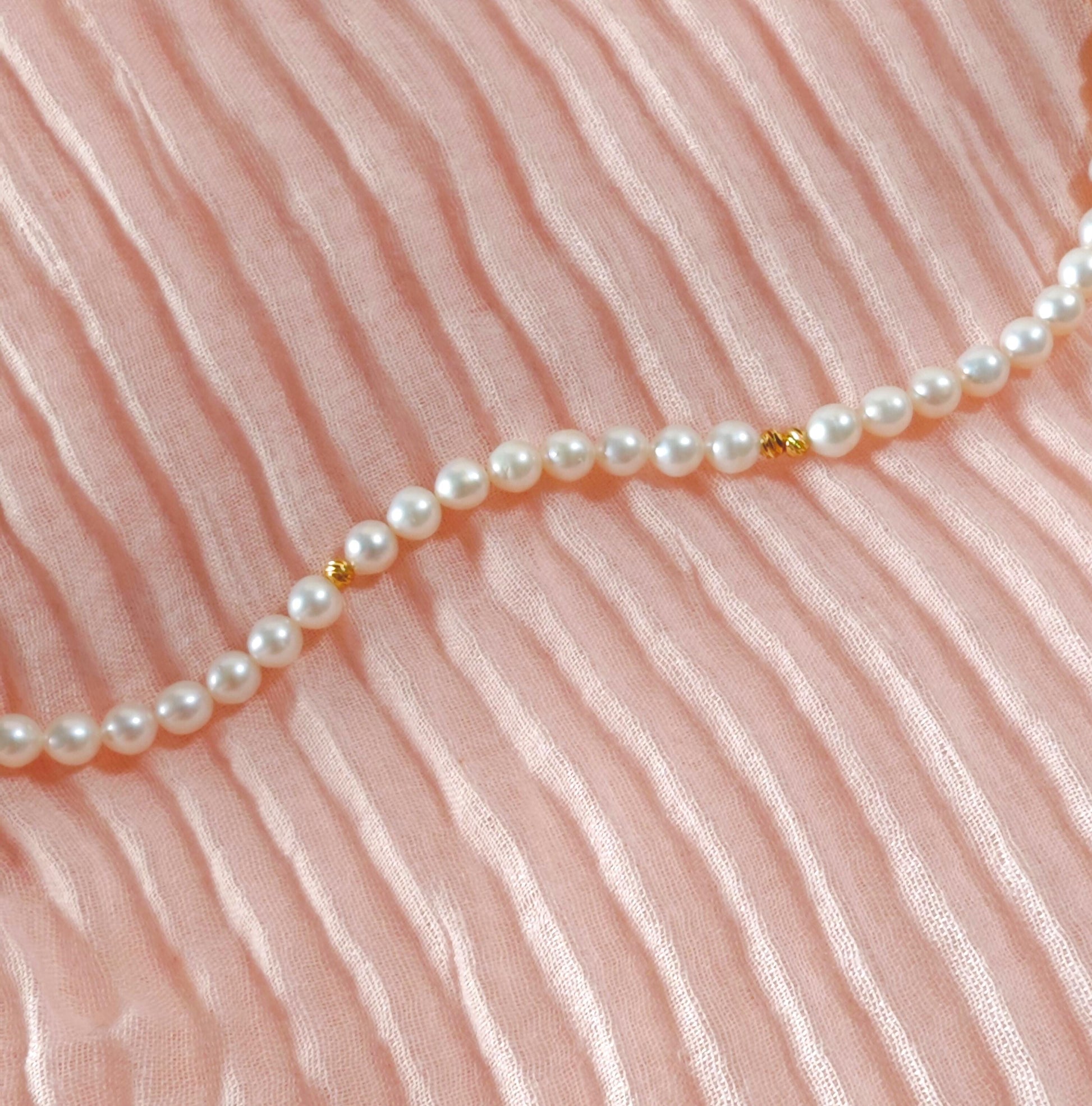 Pearl necklace on a pink fabric background