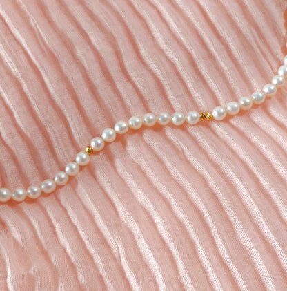 Pearl necklace on a pink fabric background